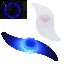 Niebieska świecąca nakładka na szprychy rowerowe na białym tle oraz zamontowana na kole roweru w nocy
