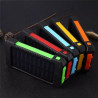 Power bank solarny czarno-pomarańczowy z panelem słonecznym i białym kablem USB