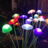 Dwie zielone lampki solarne w kształcie grzybków meduz z ciepłym światłem LED, włożone w ziemię