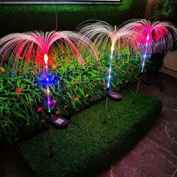 Dwie lampy solarne w kształcie palm z kolorowym światłem LED wieczorem